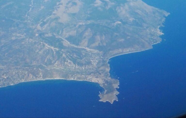 Veduta aerea di Capo Palinuro: il promontorio che si allunga nel mare blu, con l'abitato di Palinuro e la lunga spiaggia del golfo alle spalle