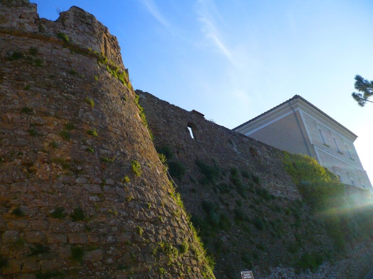 Torre rotonda e mura in pietra del Castello dell'Abate, con l'edificio del castello sullo sfondo