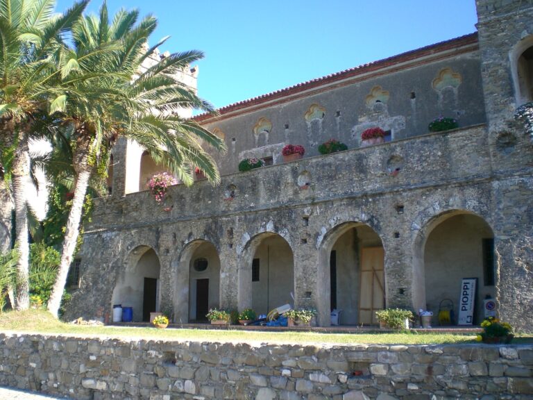 Palazzo Vinciprova a Pioppi, sede del Museo Vivente della Dieta Mediterranea al primo piano: la facciata in pietra con le arcate, le palme e i fiori sui balconi