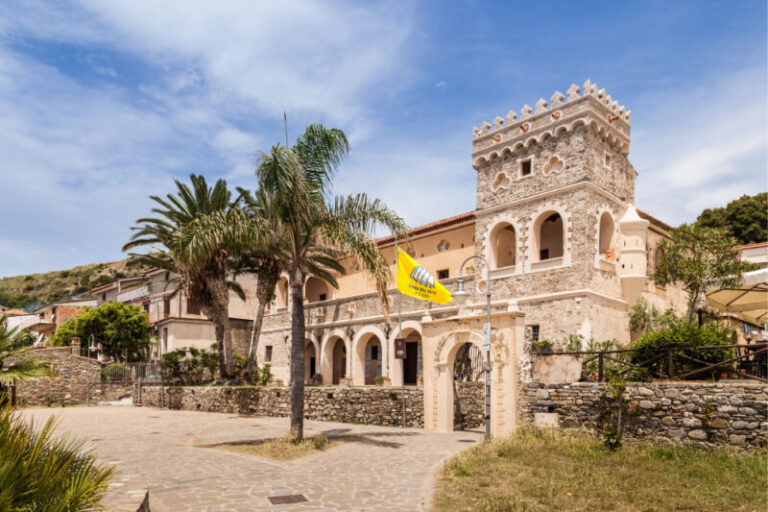 Palazzo Vinciprova a Pioppi: la torre merlata, il portico ad archi e le palme sulla piazza